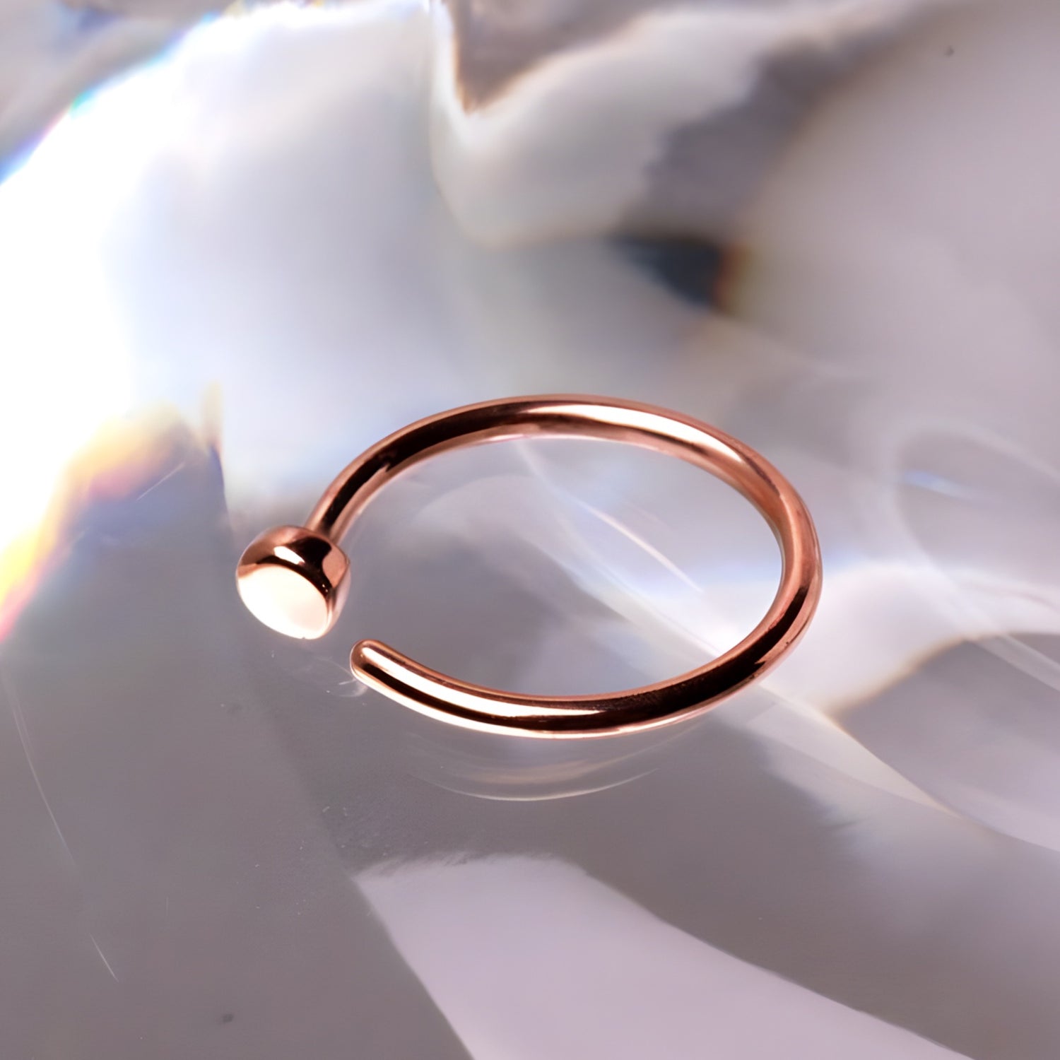 14k Rose Gold Nose Hoop Ring- Close up, gray marbled background